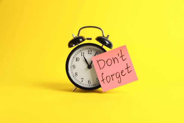 istock Alarm clock and reminder note with phrase Don't forget on yellow background 1328810061