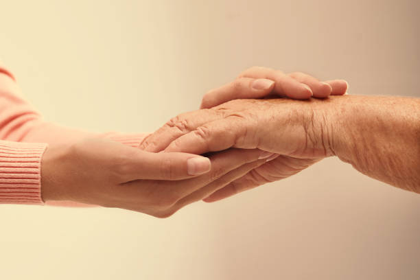istock Helping hands on light background, closeup. Elderly care concept 1328810664
