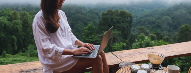 istock a woman using and working on laptop computer while sitting on balcony with a beautiful nature view on foggy day 1328814946
