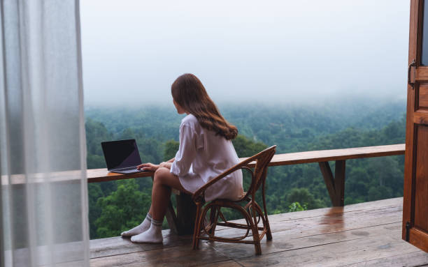 istock a woman using and working on laptop computer while sitting on balcony with a beautiful nature view on foggy day 1328814953