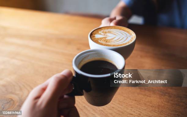 A Man And A Woman Clinking White Coffee Mugs In Cafe Stock Photo - Download Image Now