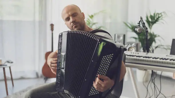 Musician in his studio at home, he is playing the accordion, arts and creativity concept