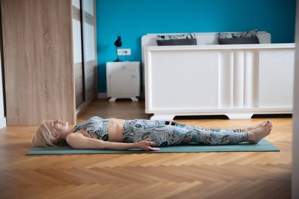 istock Woman lying on back on exercise mat in bedroom, preparing for exercise 1328819338