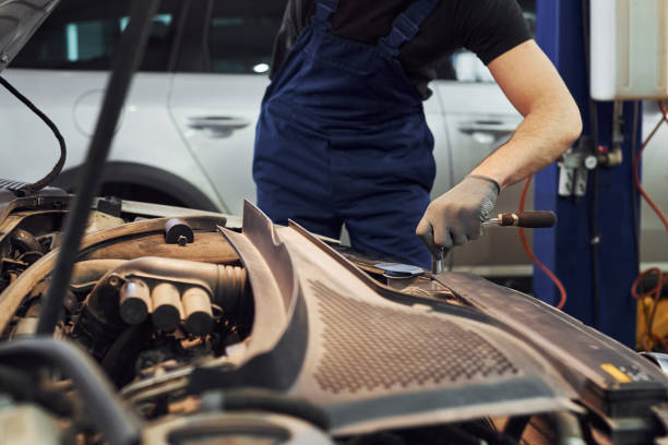 istock Man in work uniform repairs car indoors. Conception of automobile service 1328820602