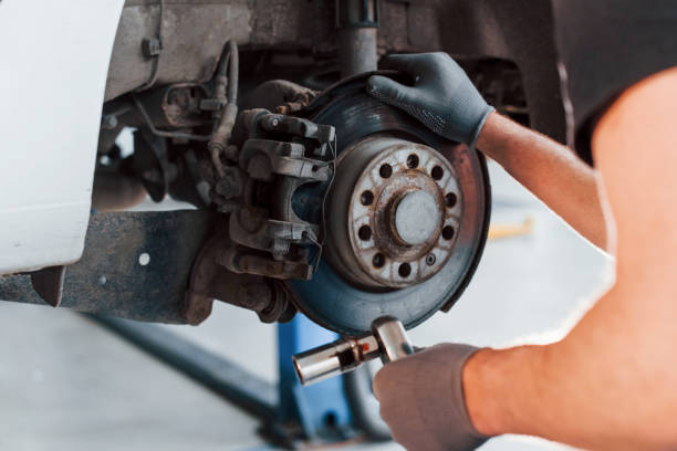 istock Man in work uniform repairs car indoors. Conception of automobile service 1328820621