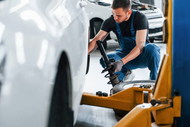 istock Man in work uniform repairs car indoors. Conception of automobile service 1328820860