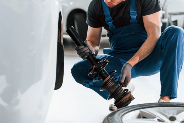 istock Close up view of man in work uniform that repairs white automobile indoors. Conception of automobile service 1328820868