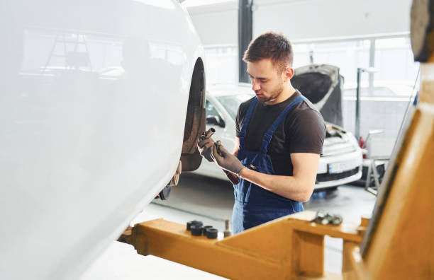 istock Man in work uniform repairs car indoors. Conception of automobile service 1328820932
