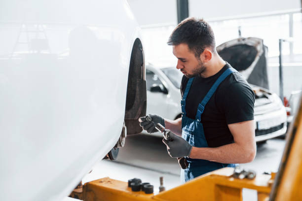 istock Man in work uniform repairs car indoors. Conception of automobile service 1328820959