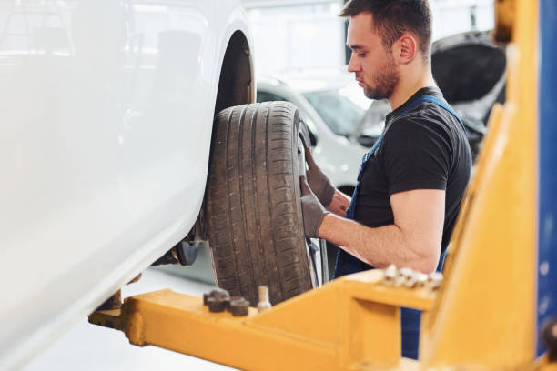 istock Man in work uniform changing car wheel indoors. Conception of automobile service 1328821006