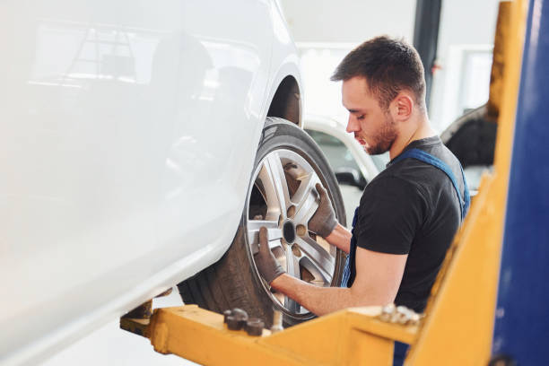 istock Man in work uniform changing car wheel indoors. Conception of automobile service 1328821030