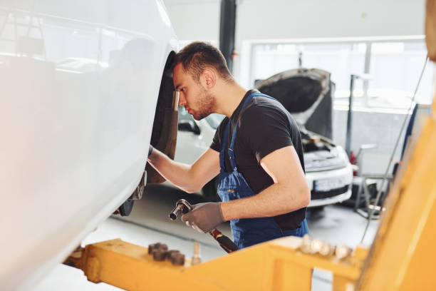 istock Man in work uniform repairs car indoors. Conception of automobile service 1328821032