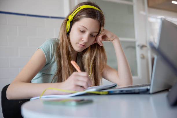 istock Teenage girl sitting at home and doing classwork, remote learning 1328821200