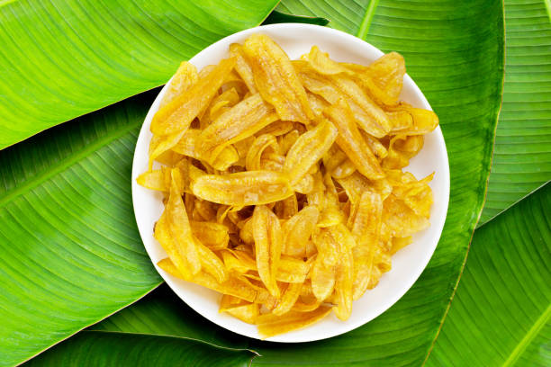 istock Banana slice chips in white plate on banana leaves background. 1328822400