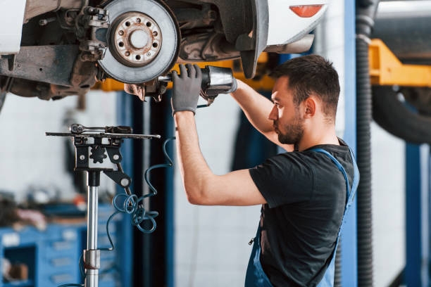 istock Using special tool. Man in work uniform repairs white automobile indoors. Conception of car service 1328822682