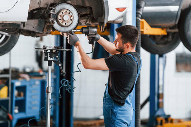 istock Using special tool. Man in work uniform repairs white automobile indoors. Conception of car service 1328822788