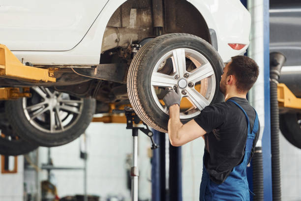 istock Man in work uniform changing car wheel indoors. Conception of automobile service 1328822810