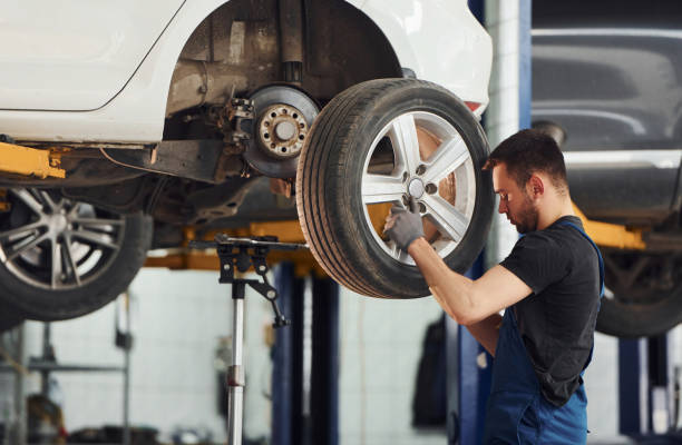 istock Man in work uniform changing car wheel indoors. Conception of automobile service 1328822868