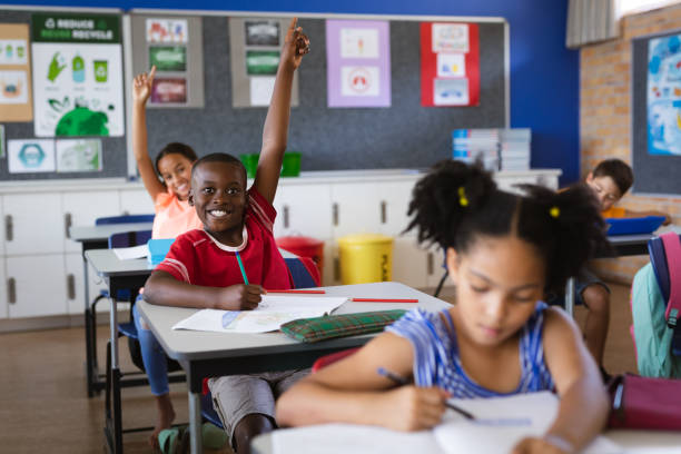 istock African american boy and girl raising their hands while sitting in the class at elementary school 1328823183