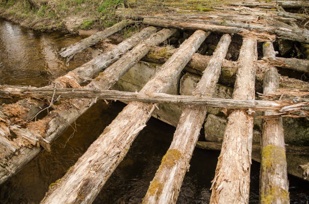 istock An old, worn, dangerous wooden bridge over a small river 1328824495