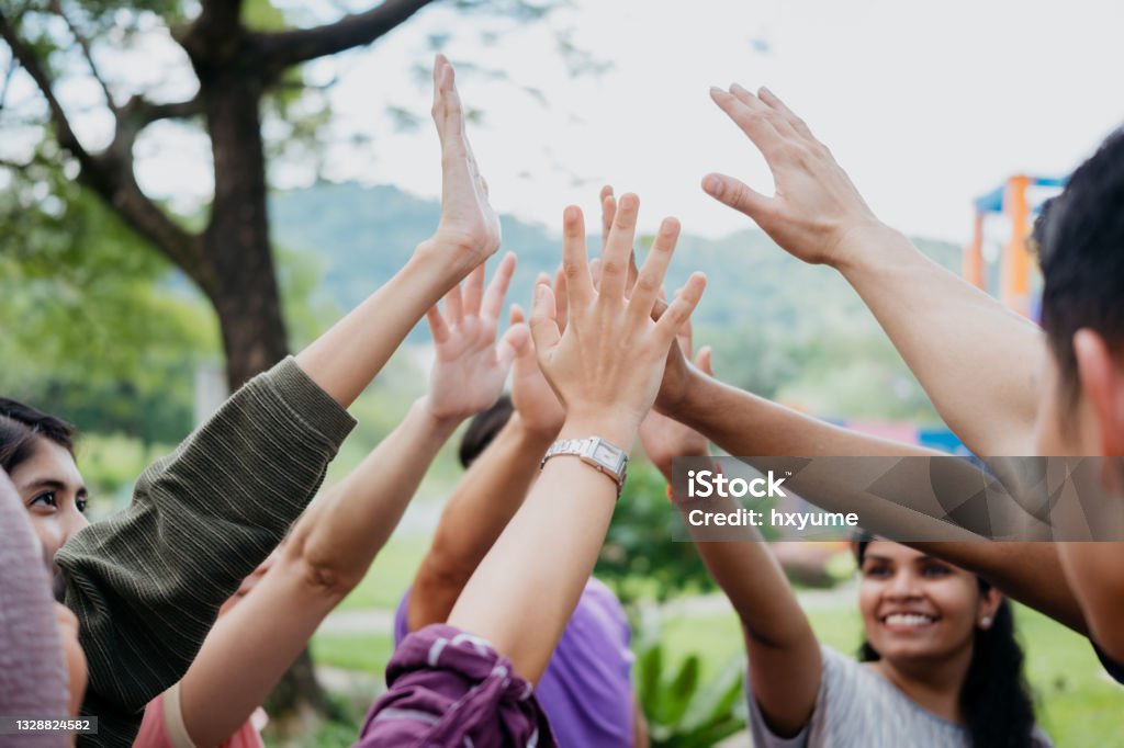 Multi ethnic asian people giving each other a high five Image of a group of multi racial asian people giving each other a high five at public park Group Of People Stock Photo