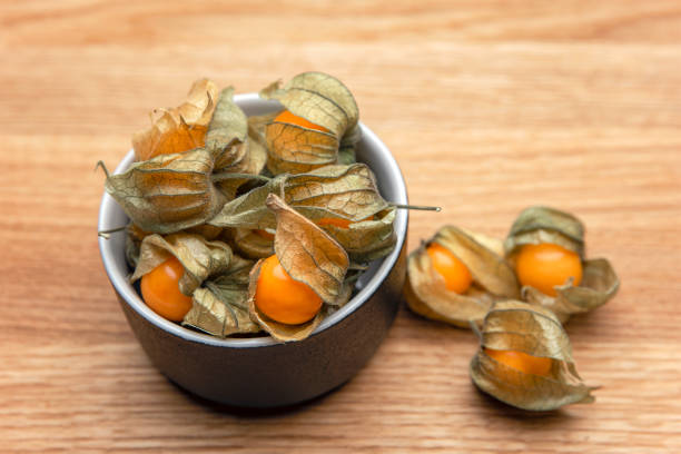 fruits physalis sur une table en bois. baies de physalis jaune doux dans une tasse sur fond de bois - cape gooseberries photos et images de collection