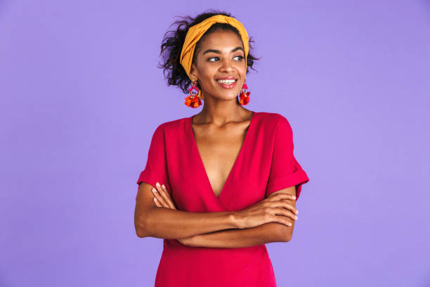 Portrait of a smiling young african woman Portrait of a smiling young african woman in headband standing over violet background, looking away isolated color photos stock pictures, royalty-free photos & images