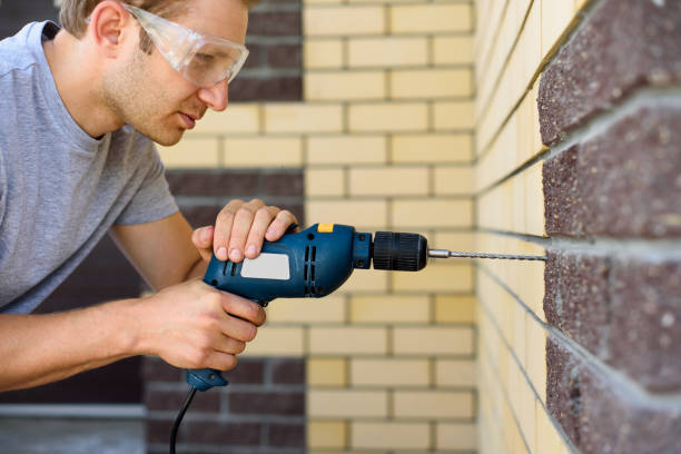 istock A man in goggles drills a brick wall with a drill. Do it yourself 1328833713
