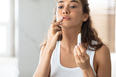 Young Lady Applying Lip Balm Moisturizing Skin In Bathroom Indoors