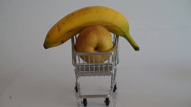 istock Banana and a pear inside a shopping car 1328835110