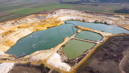 Gravel and sand open pit mining, pond with sediments - aerial view