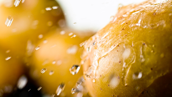 Close-up of water droplets raw potatoes against white background.