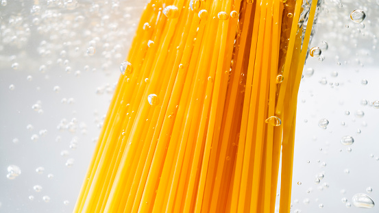 Close-up of spaghetti falling into a pot of boiling water.