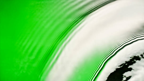 Overhead view of ripples forming on the green and yellow coloured water surface.