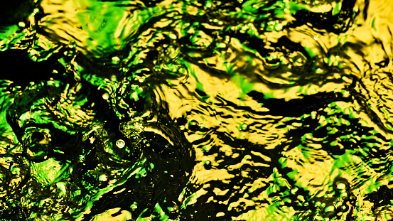 Overhead view of bubbles appearing on the green and yellow coloured water surface.
