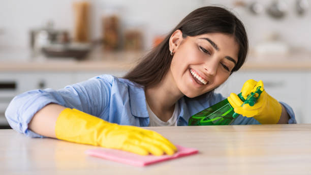 istock Cheerful young woman cleaning dining table at kitchen 1328839900
