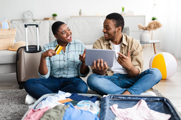 istock Black Tourists Using Tablet And Credit Card Booking Tickets Indoor 1328839955