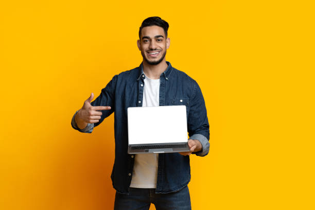 istock Cheerful arab guy pointing at laptop with blank screen 1328840020