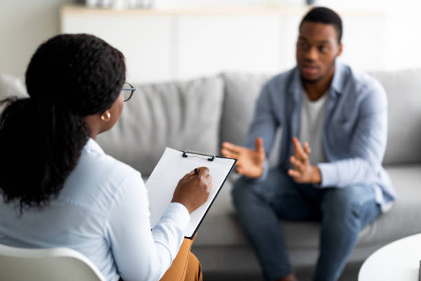 istock Psychological assistance. Millennial black man with depression having counseling session with therapist at office 1328840426