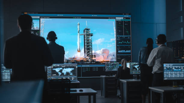 istock Group of People in Mission Control Center Witness Successful Space Rocket Launch. Flight Control Employees Sit in Front Computer Displays and Monitor the Crewed Mission. Team Stand Up and Clap Hands. 1328842075