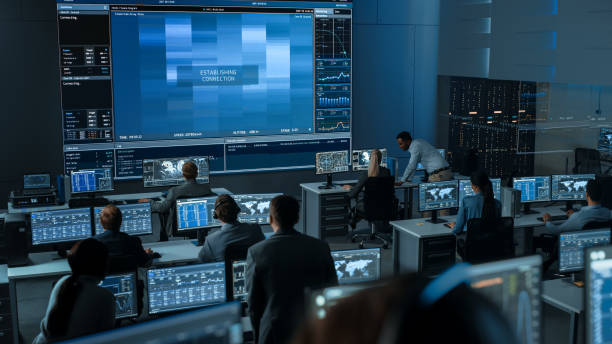 grupa ludzi w mission control center próbuje ustanowić połączenie wideo na dużym ekranie z astronautą na pokładzie stacji kosmicznej. flight control naukowcy siedzą w przednich wyświetlaczach komputerowych. - control room audio zdjęcia i obrazy z banku zdjęć