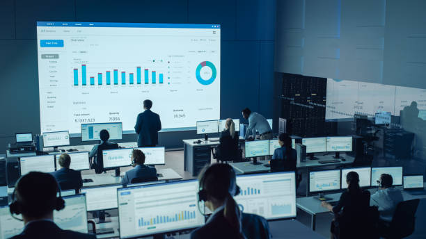 istock Professional Traders Working in a Modern Monitoring Office with Live Analytics Feed on a Big Digital Screen. Monitoring Room with Brokers and Finance Specialists Sit in Front of Computers. 1328842114