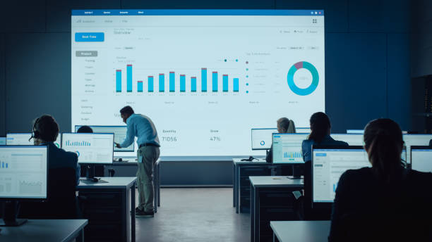 istock Professional Traders Working in a Modern Monitoring Office with Live Analytics Feed on a Big Digital Screen. Monitoring Room with Brokers and Finance Specialists Sit in Front of Computers. 1328842152