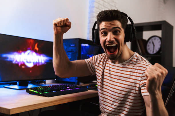istock Cheerful gamer playing video games on computer and rejoices 1328843693