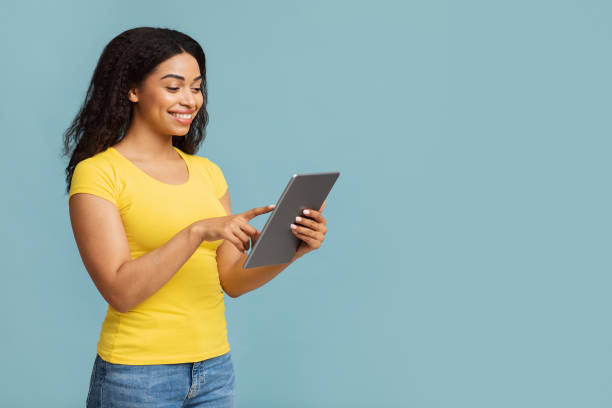 istock Technologies and entertainment concept. Excited black lady with digital tablet standing on blue background, empty space 1328843743