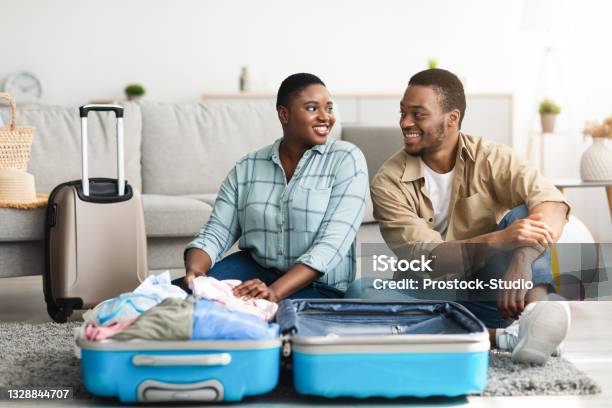 African American Couple Packing Suitcase Sitting On Floor At Home Stock Photo - Download Image Now