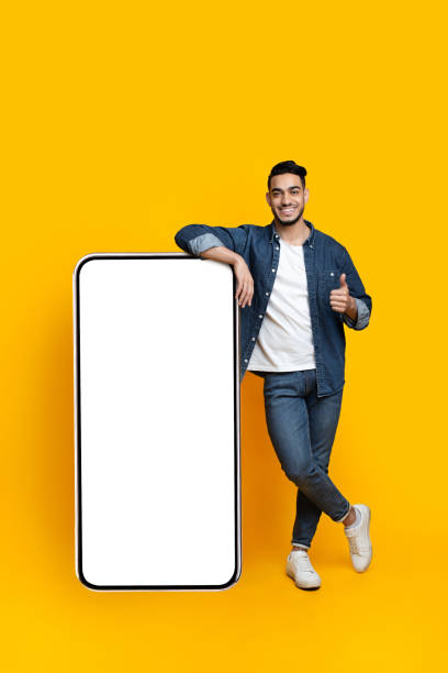 istock Happy arab guy leaning on huge smartphone, mockup 1328844797