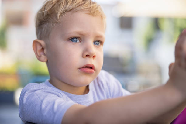 Headshot of blond toddler with blue eyes playing outside and looking away