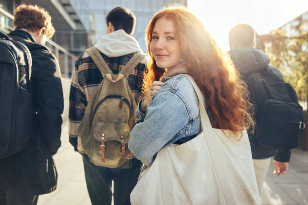 Female student going for class in high school Female student glancing back while going for a class in college. Girl walking with friends going for class in high school. youth culture stock pictures, royalty-free photos & images