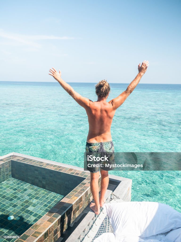 Best vacation ever!! Man enjoying tropical vacations in an infinity pool in private over water villa. People travel luxury holidays Beach Stock Photo